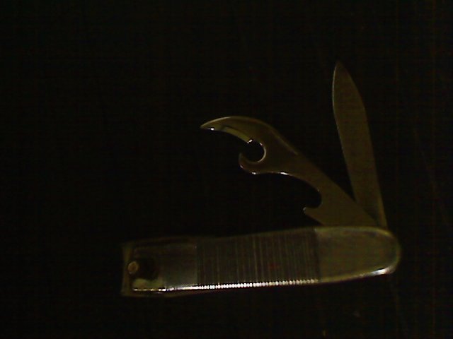 Nail clipper on black background showing can opener blade and nail cleaning blade.